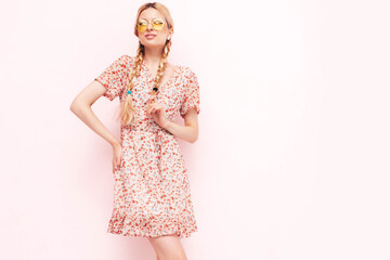 Young beautiful smiling female in trendy summer dress. Sexy carefree blond  woman posing near wall in studio. Positive model having fun. Cheerful and happy