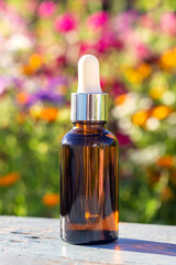 Brown glass dropper bottle with serum, essential oil or other cosmetic product on bright floral background. Natural Organic Spa Cosmetic Beauty Concept Mockup Front view