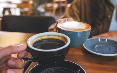 Closeup image of a couple people clinking coffee cups together in cafe