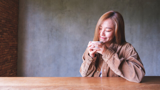 Portrait image of a beautiful young asian woman holding and drinking hot coffee