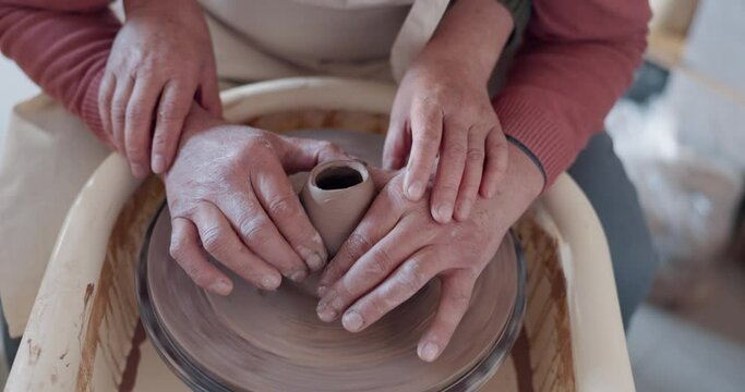 Love, pottery and hands of old couple molding in workshop studio for creative art, support and ceramics class. Trust, marriage and retirement with man and woman with clay wheel on crafting date