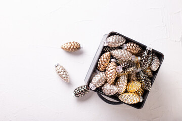 Background with Christmas decorations. Glass gold, black, silver decorative cones in metallic box on white  textured background. Scandinavian minimalistic style. Still life. Top view.