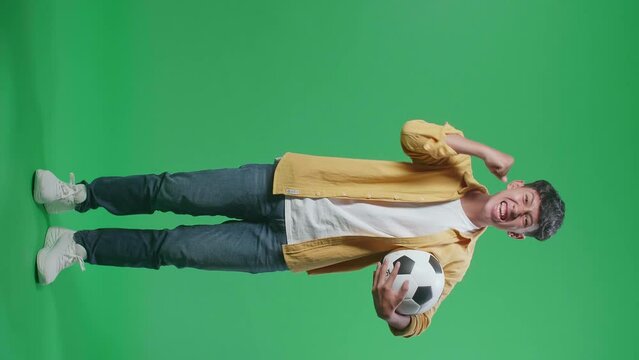 Full Body Of Asian Boy With A Ball Screaming Goal Celebrating For The Winner Team While Cheering Soccer On Green Screen Background
