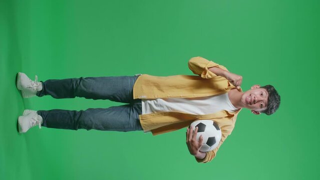 Full Body Of Excited Asian Boy With A Ball Is Rooting For Shooting At Goal While Cheering Soccer On Green Screen Background
