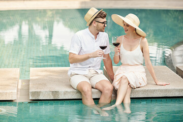 Couple drinking ine at outdoor pool