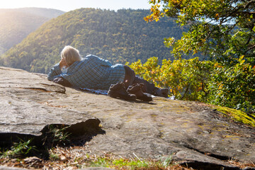 Goldener Oktober: Wanderer sonnt sich auf einem Fels im Pfälzerwald in der warmen Oktober-Sonne