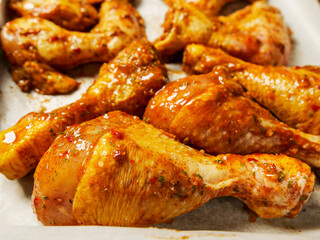 Close up shot of Asian style marinated chicken wings and drumstick ready to be cooked on a white cooking paper and metal tray. Chicken meat poultry product.