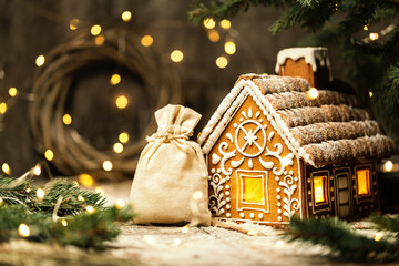 Christmas Santa Bag with Gifts next to Gingerbread House. White Burlap Sack with Xmas Presents over...