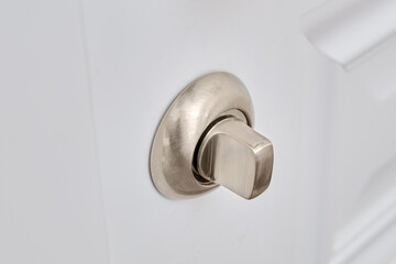 A white door with a lock in the home room and a light switch. Metal lock handle in the apartment