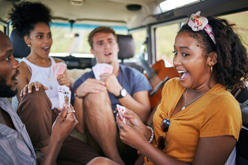 Playing cards, road trip and friends in van winning and excited for adventure journey, holiday and...