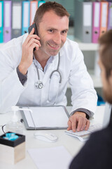 Fototapeta premium male doctor using telephone during consultation with patient