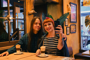 Attractive and stylish couple taking a selfie in a cafe while they are dunking a cappuccino