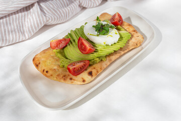 Avocado Sandwich with Poached Egg - sliced avocado and egg on toasted bread for healthy breakfast or snack, copy space.