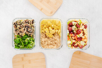 Batch cooking. Cuisiner par lots. Recipients en verre, couvercle bambou. Préparation des repas de la semaine. Entrée, plat et dessert. Repas équilibré. Zero déchet. Menu à emporter. Fond blanc.