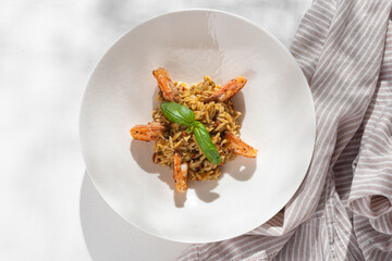 Orzo pasta with shrimps on white background for restaurant menu. Flat lay.