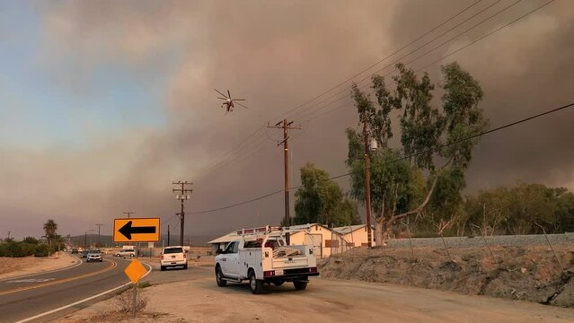 Elivis fire water bombing helicopter appears out of the smoke and flies overhead
