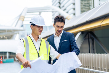 Caucasian businessman and Asian worker working in outdoors in city. 