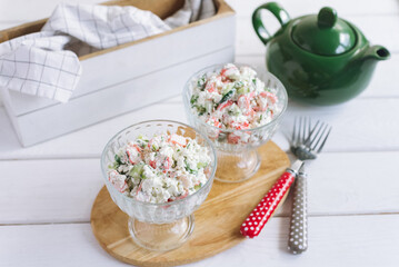 Cottage Cheese Crab Salad. Tender and light salad with cottage cheese, fresh cucumber, chopped greens and crab sticks. Two glass salad bowls. A simple summer season salad.