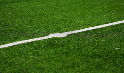 Close up detail field of the artificial grass from a brand new soccer field, view with the white marking line.
