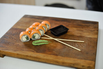 sushi roll with salmon, cucumber and wasabi on wooden board