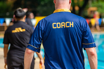 Back view of swimming coaches, wearing COACH shirt