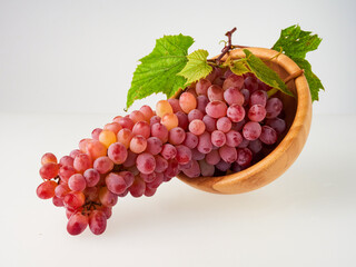 Fototapeta premium Ripe red grapes. Pink bunch with leaves isolated on white. With trajectory cropping. Full depth of field.