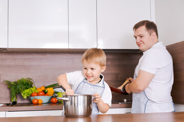 Family cooking in household dad with son, cook dinner for mom, have fun together. Father teaches son to help