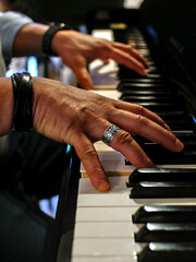 Close up on a hand playing piano. Other hand is blurry.