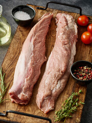 Filet Mignon of raw pork. Raw pork fillet tenderloin on wooden board with spices, grey background.