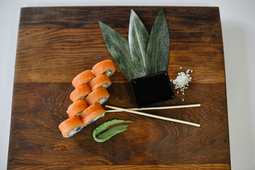 sushi roll with salmon, avocado, cucumber and wasabi on wooden board