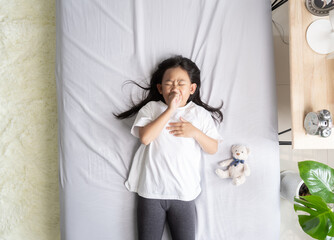 Top view Asian child girl sick with sneezing on the nose and cold cough, Sick child with fever and illness in bed.