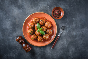 Homemade meatballs with tomato sauce and spices served in plate on grey background
