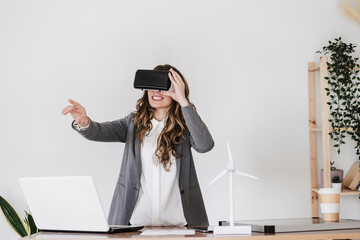 Gesturing young businesswoman using virtual reality simultor in office