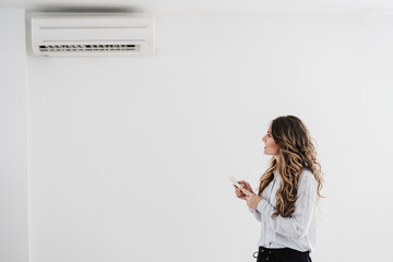 Businesswoman switching on air conditioning in the office