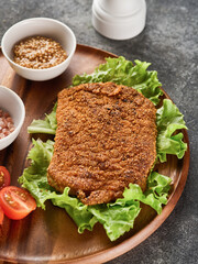 Breaded pork cutlet with cherry tomatoes, mustard and lemon.