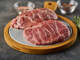 Fresh raw pork cheeks with salt and pepper. Grey background