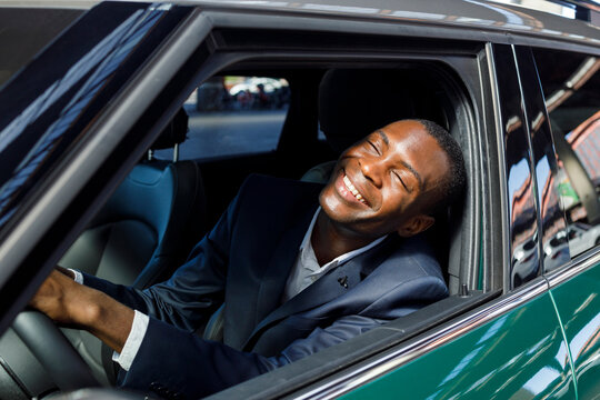 Cheerful businessman with eyes closed enjoying sunny day through car window
