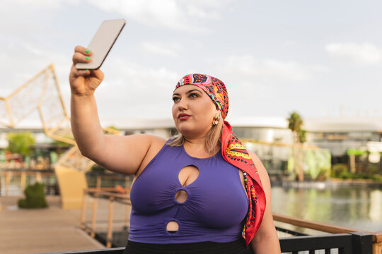 Woman wearing headscarf taking selfie through smart phone