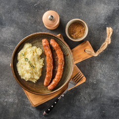 Grilled Beef bratwurst with mash potato on modern plate on wooden board.  BBQ beef sausages. German...