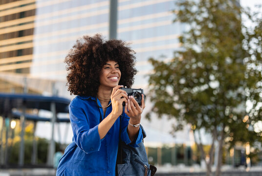 Happy Afro woman photographing through camera
