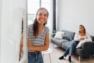Happy young woman opening door at home