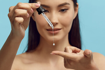 Portrait of pretty woman dripping serum on her finger. - 536917779