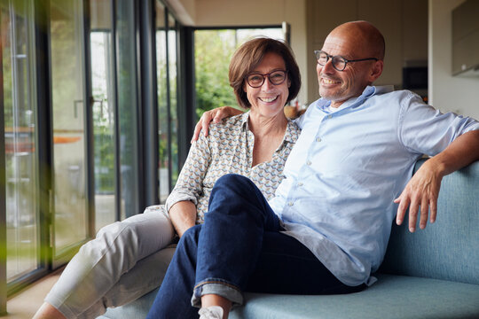 Cheerful senior couple sitting on sofa together at home