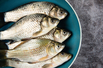 Freshly freshwater fish Crucian carp in plate on table