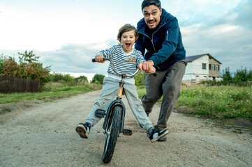 Father teaching son to ride bicycle on road