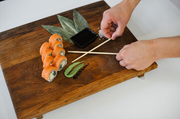 sushi rolls with salmon and chopsticks on wooden table, closeup