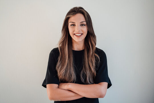 Happy young woman standing with arms crossed against white background