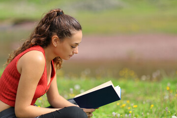 Casual woman reading a book sitting in the mountain