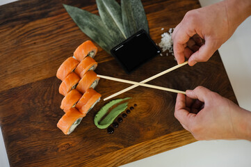 sushi set. hands of woman with salmon and chopsticks.