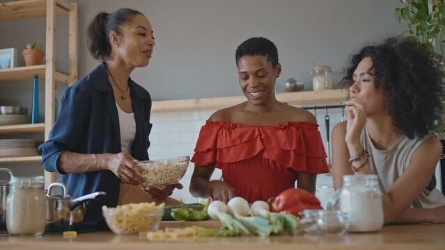 Beautiful young women spending time together and having fun. Latin and hispanic girls lifestyle moments in the kitchen while cooking. Representation of happy friends laughing and sharing good vibes